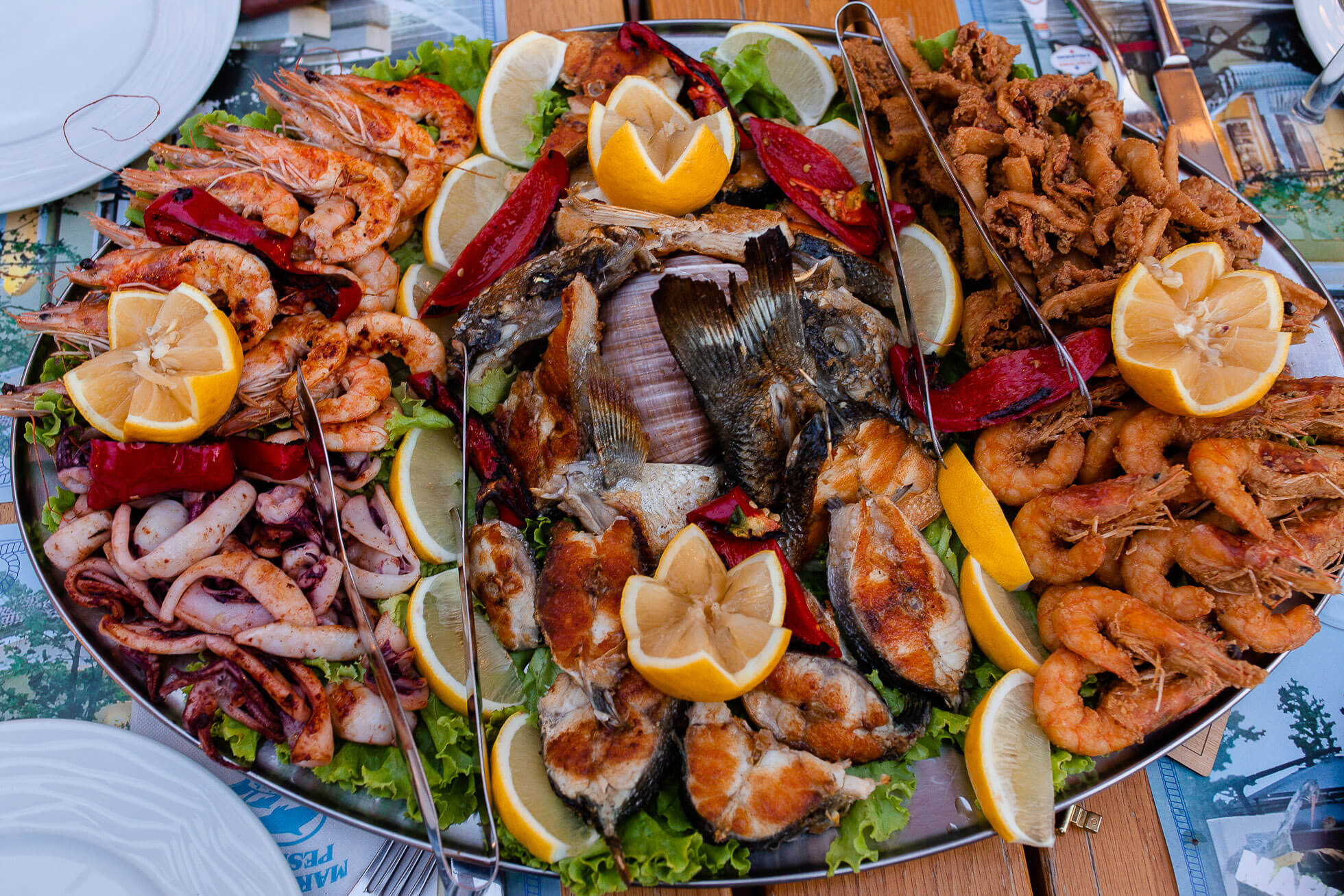 Seafood Platter with Shrimp, Octopus, Clams and other seafood with sliced lemons laying on top of the platter.