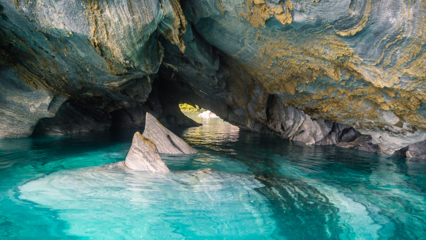 View inside the Marble Caves on General Carrera Lake in Patagonia, Chile, showing smooth, layered marble rock formations with golden streaks above clear turquoise water.