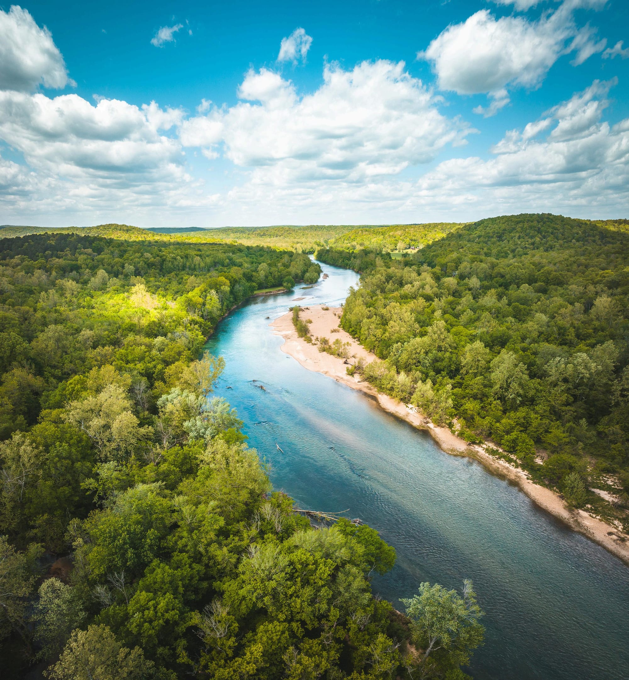 Ariel view of current river in Van Buren, Missouri winding through the forest with gravel bars on one side of the river. 