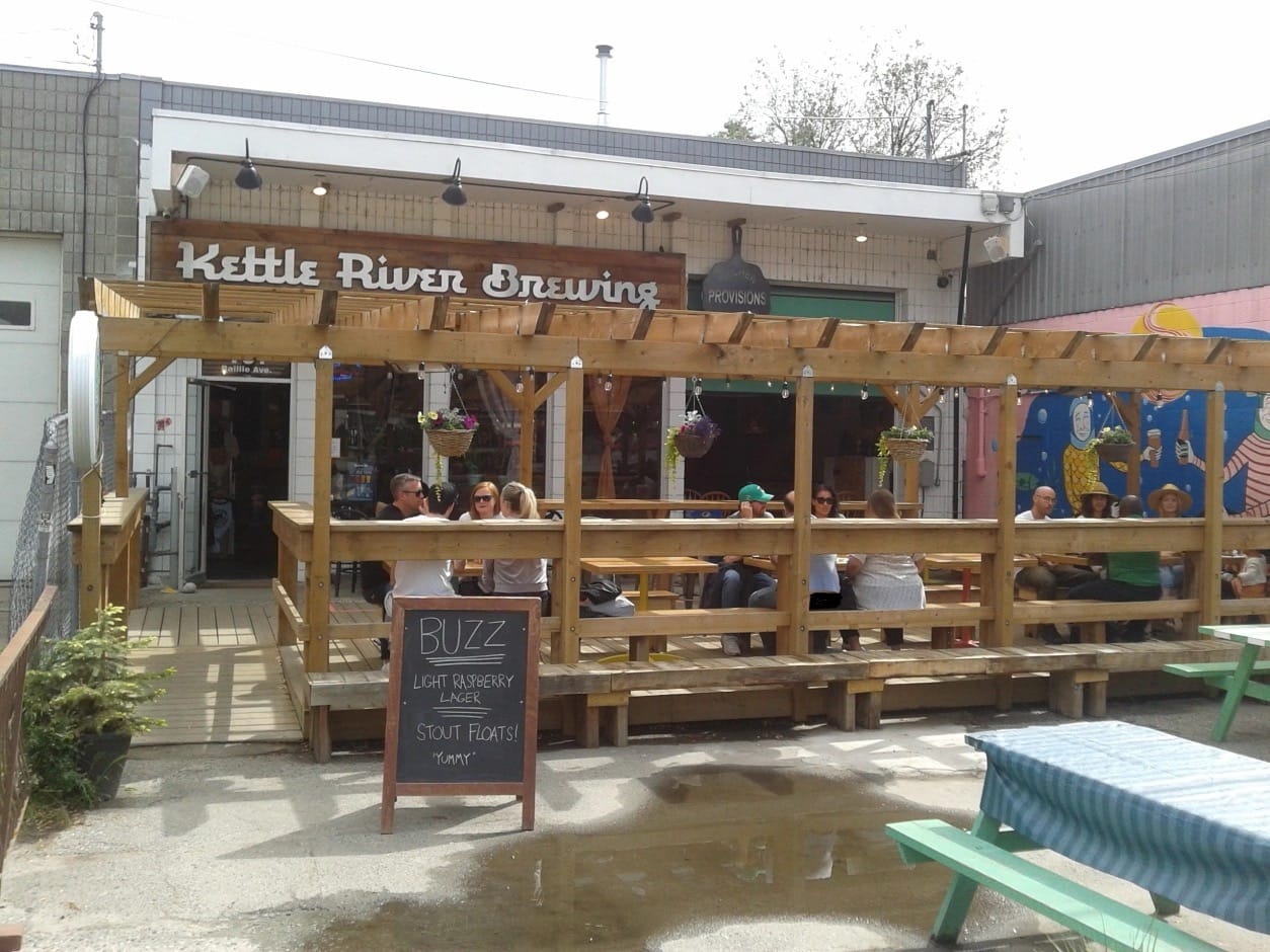 People sitting outside a place enjoying craft beers and socializing on a patio of a bar. 