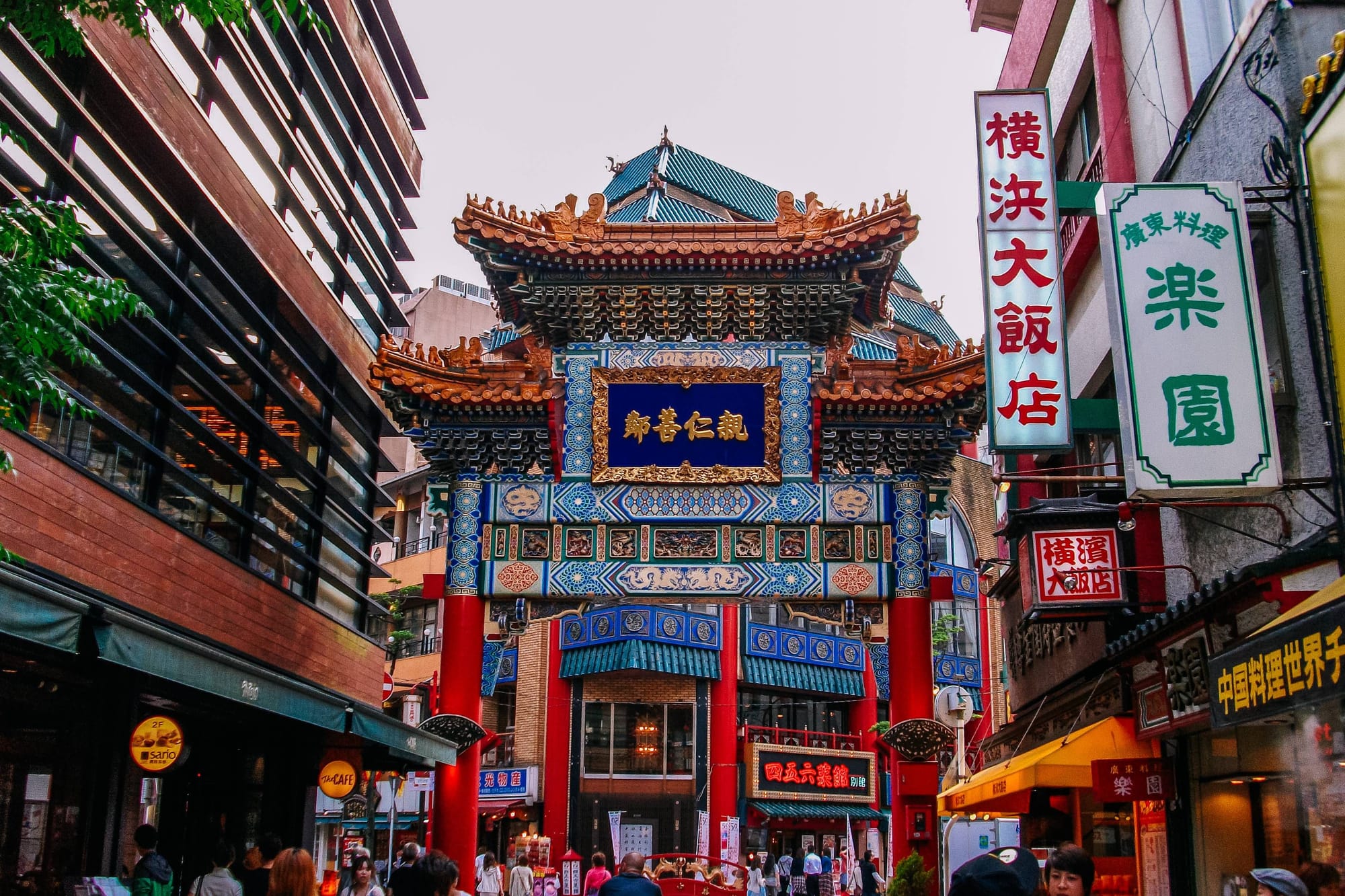 people walking around and exploring Yokohama Chinatown which has bright colored signs all over traditional Japanese buildings. 