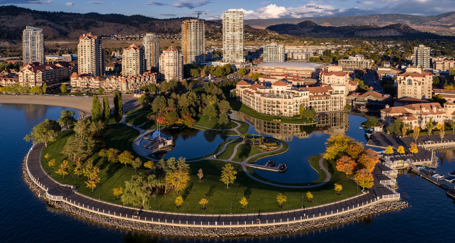 Ariel view of downtown Kelowna showing a walking path shaped like half of a circle with buildings in the background. 