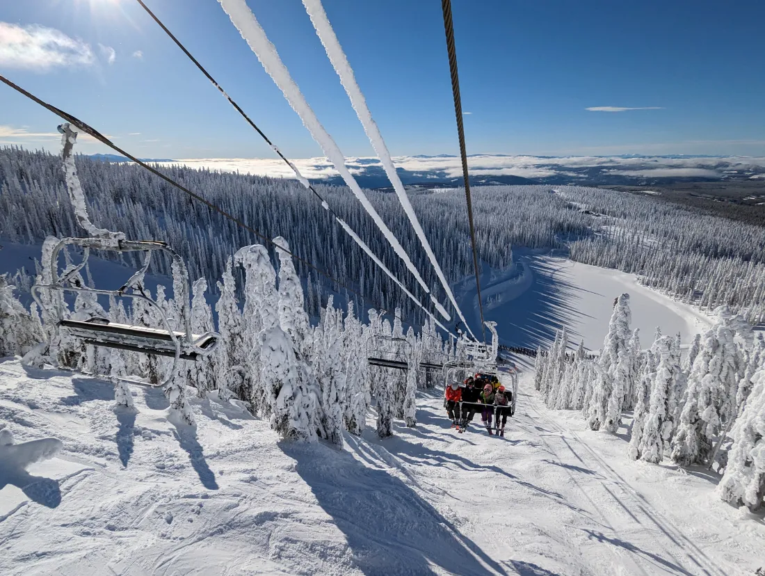 People riding a ski lift on a ski resort that is covered in fresh snow.