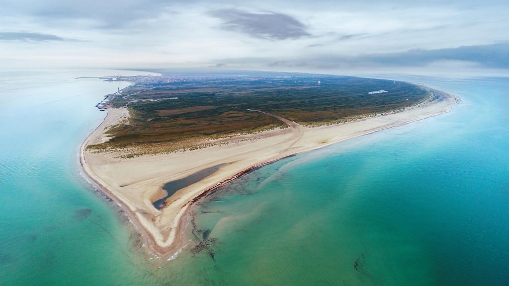 Ariel view of Skagen’s Grenen in Denmark shows a beach with clear greenish blue waters.