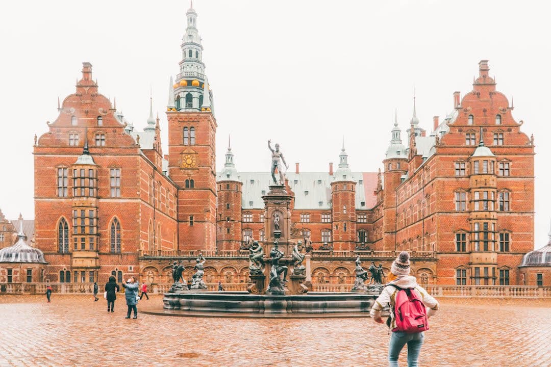 People taking photos and taking in the beauty of a large castle built in the 1600's in Copenhagen, Denmark.