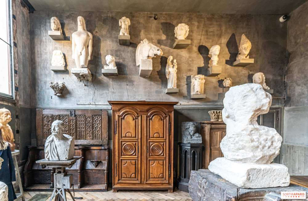 Interior of the Musée Bourdelle in Paris, France, displaying classical sculptures, busts, and unfinished works in a rustic studio setting with stone walls and wooden furniture.