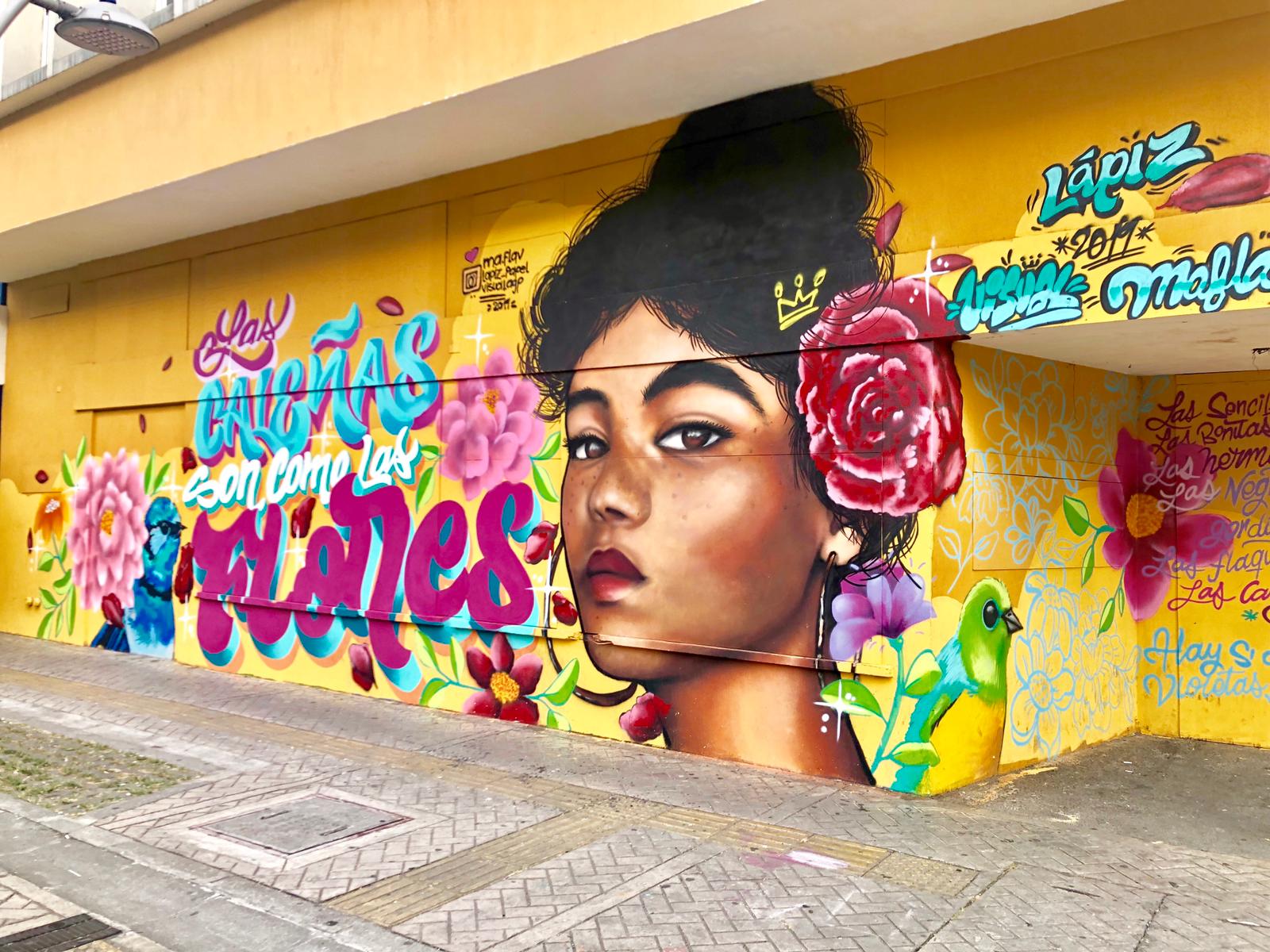 Painting of a mural of a woman on the side of a yellow building in Cali, Colombia