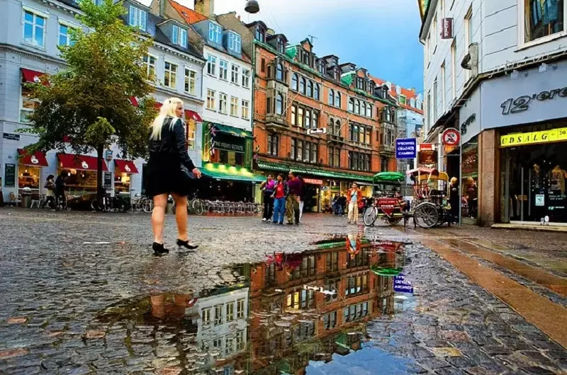 A woman walking the cobblestone streets after a rain at the Strøget shopping area in Copenhagen, Denmark. 