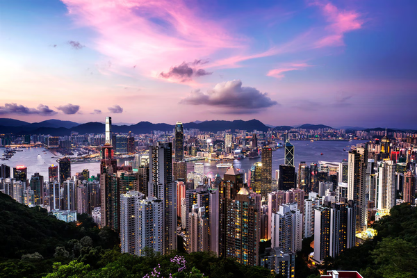 Hong Kong's Victoria peak at sunset shows the sky pink and blue above the city Skyline.