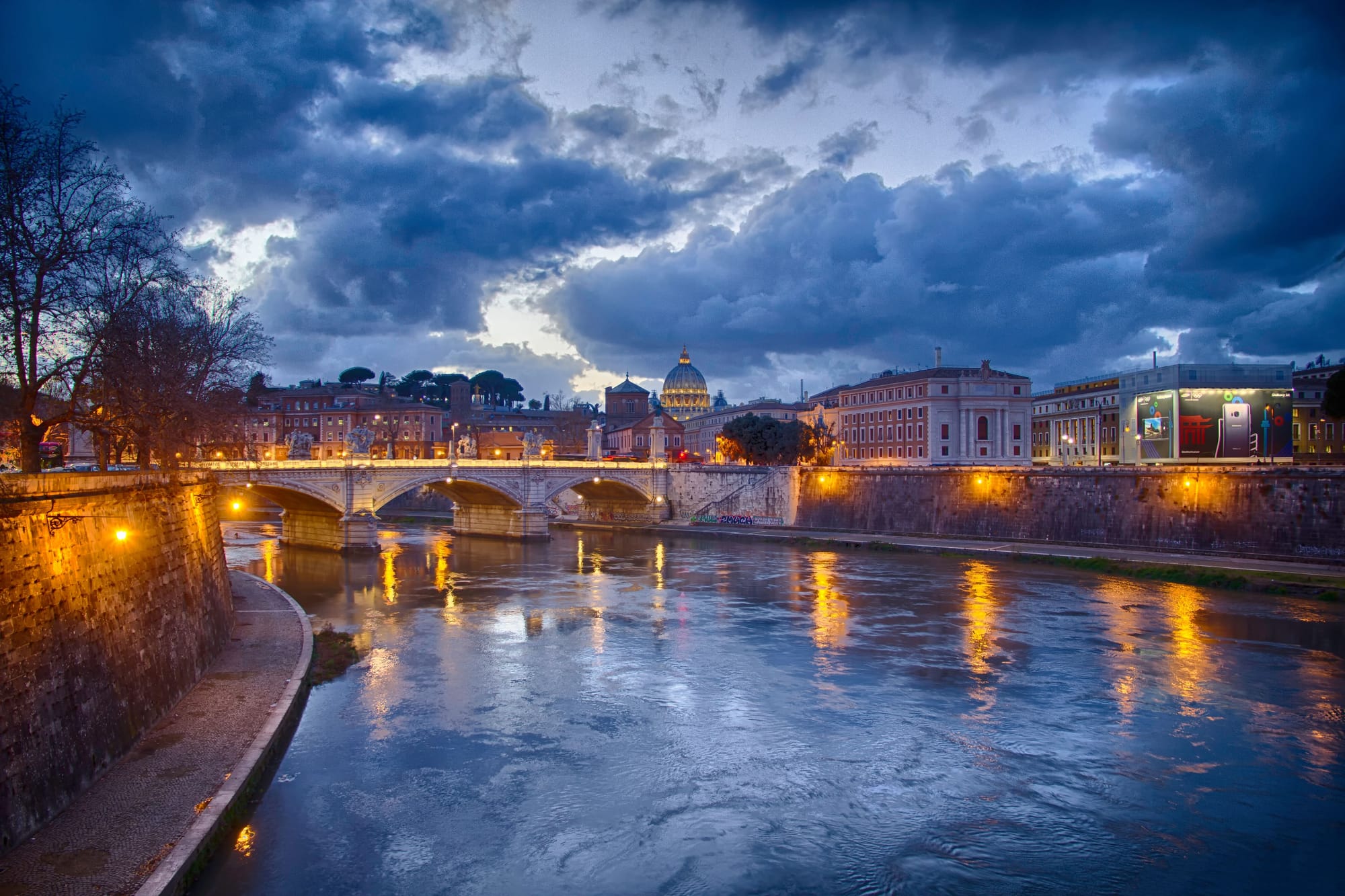 A Bridge crossing over the Tiber River in Rome At Night.