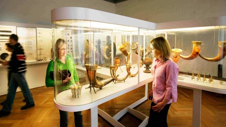 People looking at Viking horn cups behind a glass display at the National Museum of Denmark.
