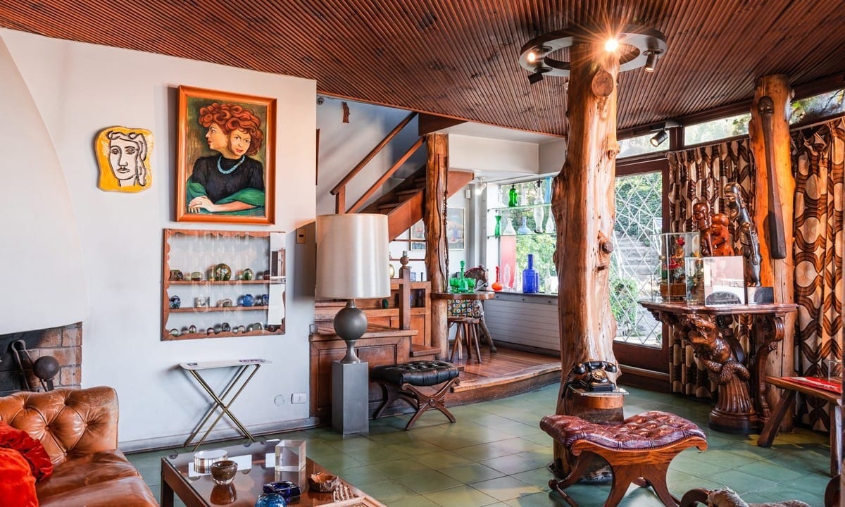 Inside of a house with a leather couch, and different artwork and paintings on the walls. 