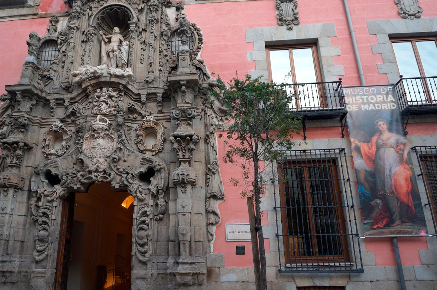 Ornate Baroque entrance to the Museo de Historia de Madrid, Spain, with detailed stone carvings and a pink facade.