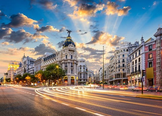 The sun shining and creating sun rays in the sky over Madrid's Gran Via area.