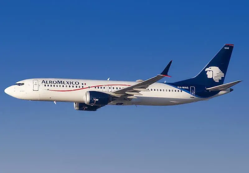 Aeromexico Boeing 737 aircraft in mid-flight with landing gear retracted, flying against a clear blue sky with the airline’s logo and branding visible on the fuselage and tail.