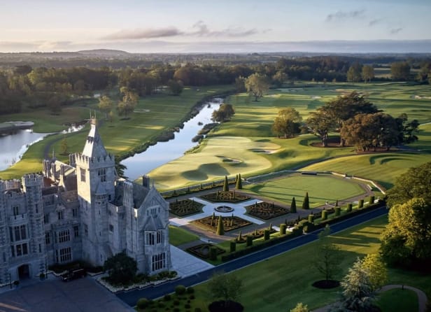 Aerial view of Adare Manor in Ireland, featuring the historic castle-like hotel, formal gardens, winding river, and lush green golf course.
