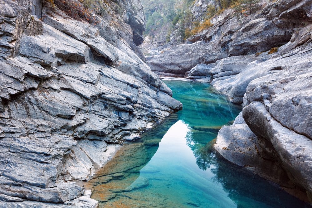 Clear turquoise river winding through a rocky canyon in Pyrenees National Park, France.