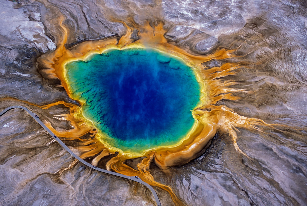 Aerial view of Grand Prismatic Spring in Yellowstone, showing vivid bands of blue, green, yellow, and orange hot spring colors.