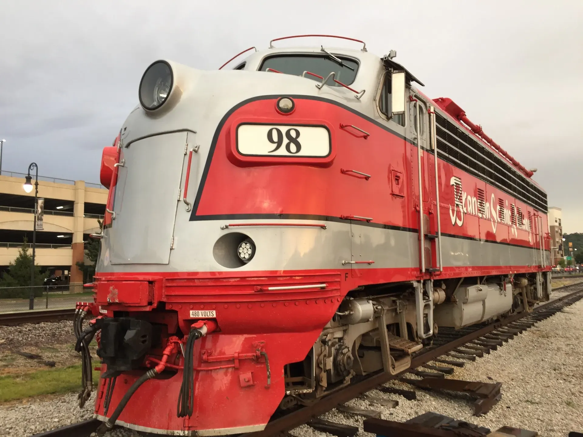 An old red and grey train sitting on the tracks in downtown Branson Missouri.