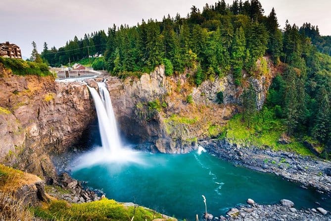 Snoqualmie Falls pouring into a turquoise pool surrounded by lush evergreens in Washington State.
