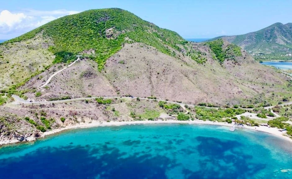 White House Bay Beach in St. Kitts is a beautiful beach with clear blue waters and surrounded by mountains.