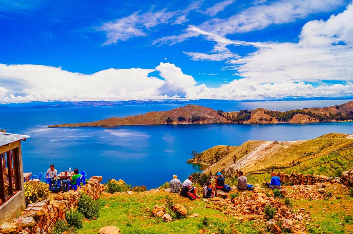 Visitors relax above the sparkling blue expanse of Lake Titicaca under wide Andean skies.