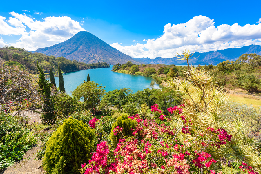 Vibrant flowers frame the volcano-ringed shores of gorgeous Lake Atitlán.