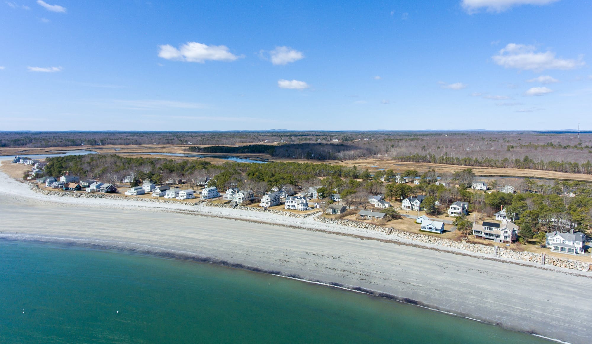 A beautiful beach with pretty sand and emerald colored waters at Goose Rocks Beach in Maine.