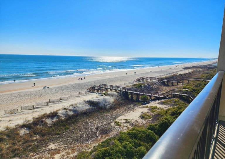 Sunset view of Litchfield Beach in Pawleys Island, South Carolina, featuring sand dunes, sea oats, a colorful sky, and a peaceful shoreline with gentle waves.
