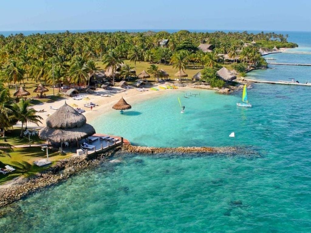 Rincón del Mar beach in Colombia—laid-back village shoreline with palm-thatched huts and calm clear blue sea.