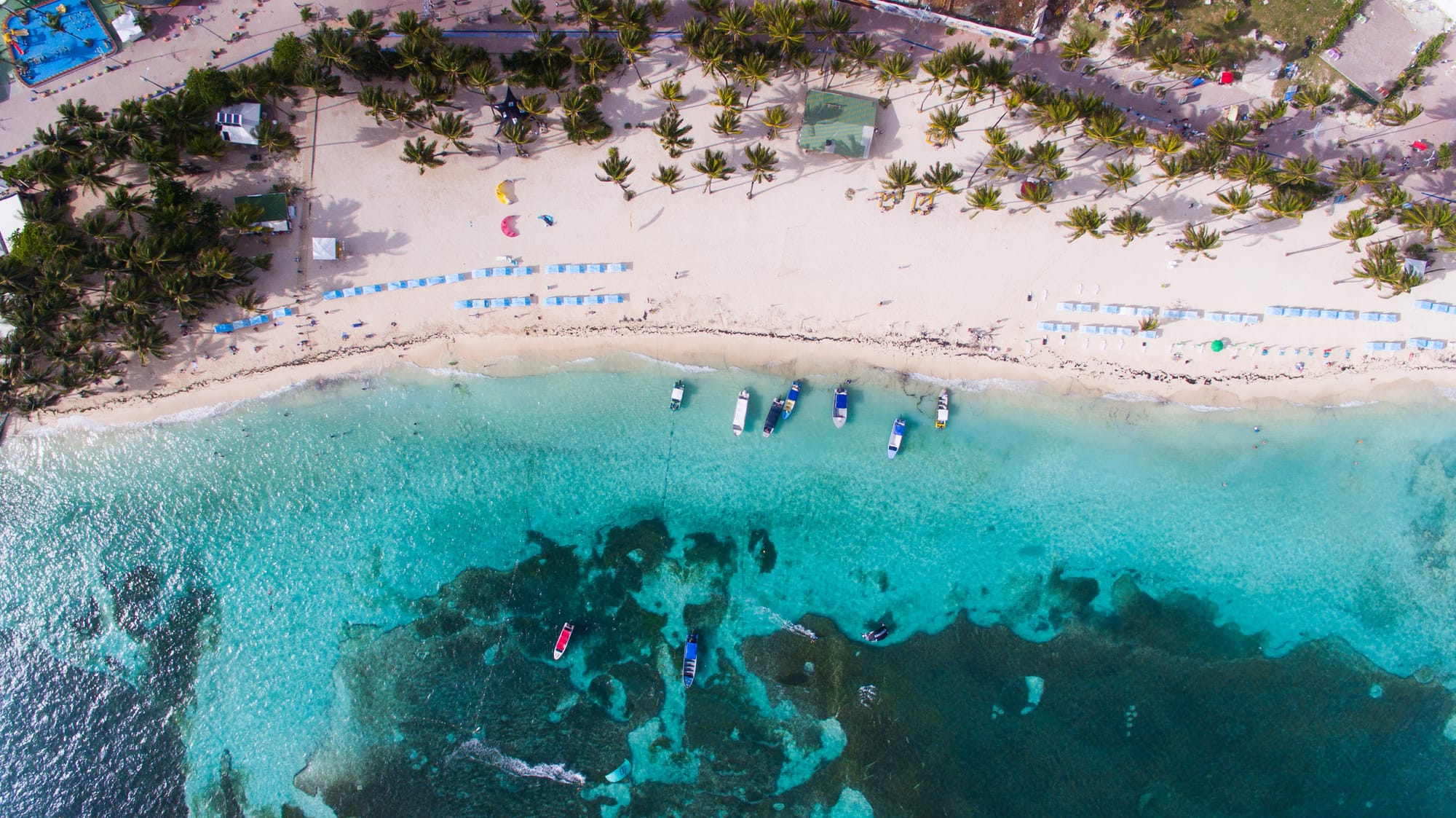 Aerial view of Spratt Bight Beach in San Andrés—white sand, shallow turquoise water, and boats anchored offshore.