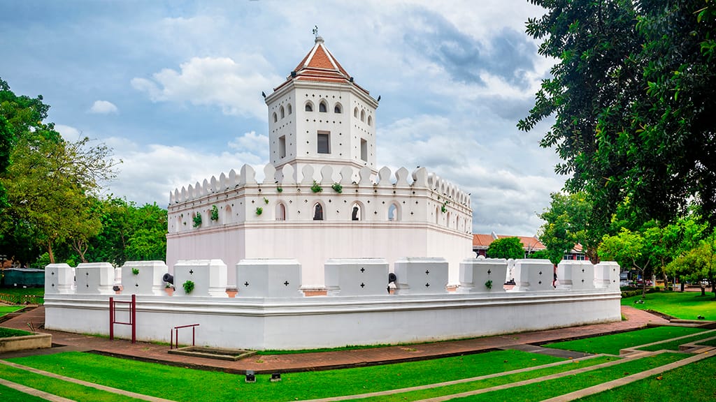 Historic white-walled Fort Phra Sumen with a central octagonal tower and battlements, located in a green park area in Bangkok, Thailand.