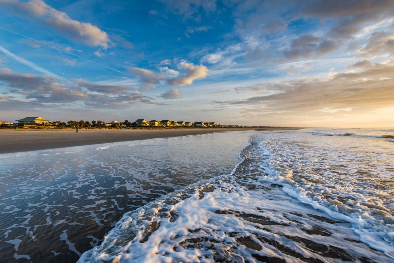 Aerial view of Isle of Palms Beach near Charleston, South Carolina, showing beach houses, light surf, and a vibrant turquoise shoreline stretching along the coast.
