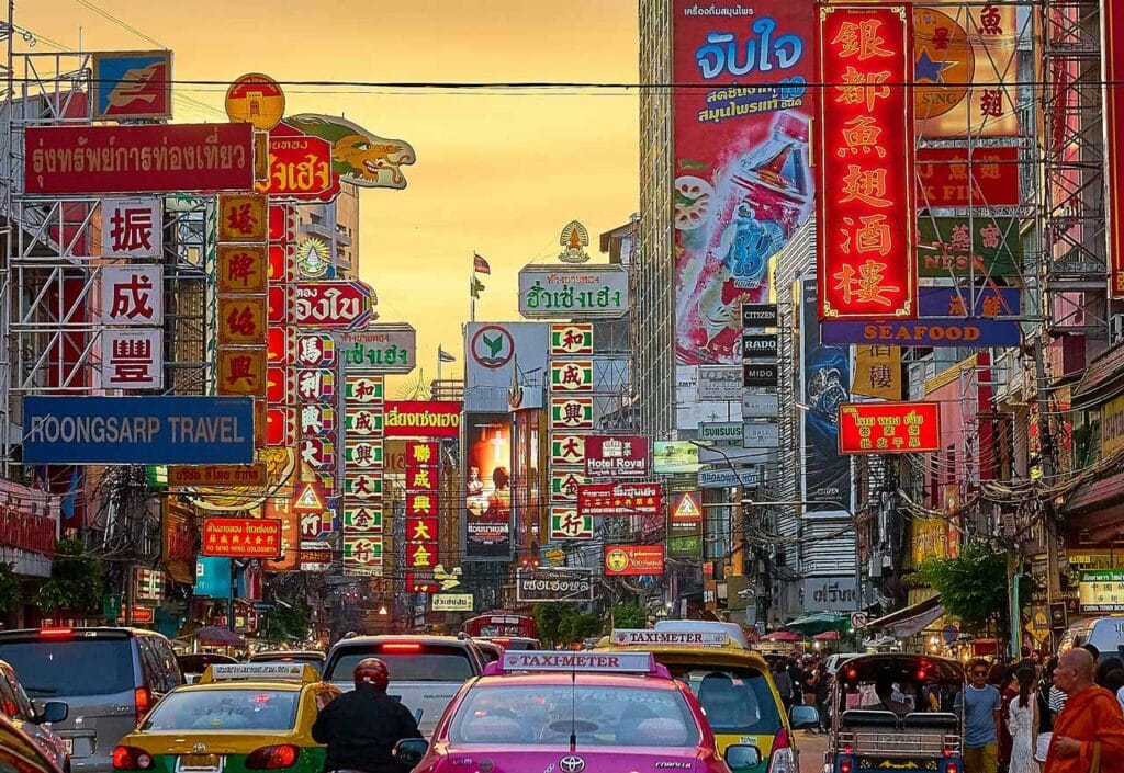 Busy street scene in Chinatown, Bangkok, Thailand, filled with colorful signs and traffic.
