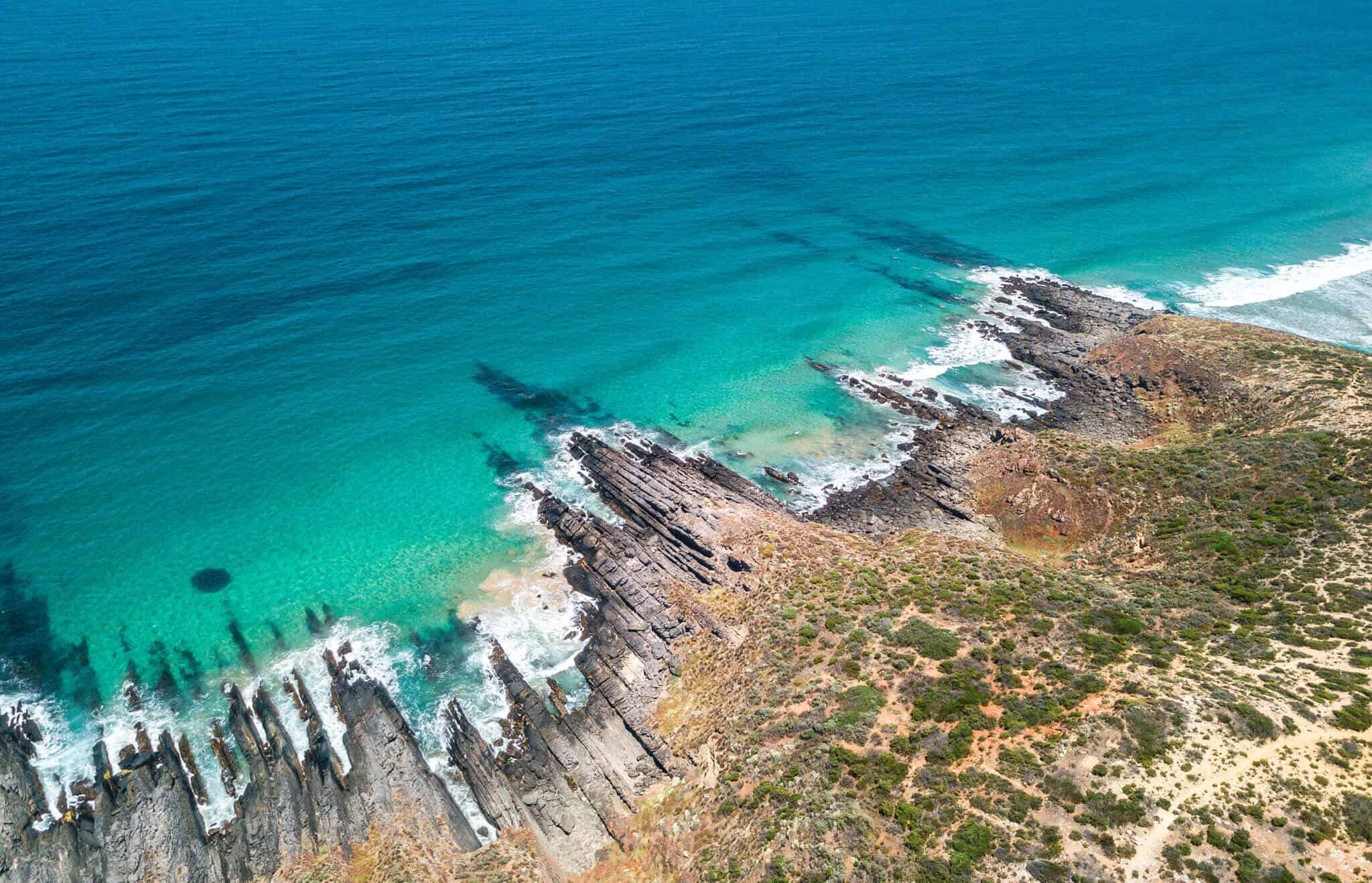 Ariel view of a rocky coastline and beautiful clear ocean waters in the Fleurieu Peninsula in Australia.