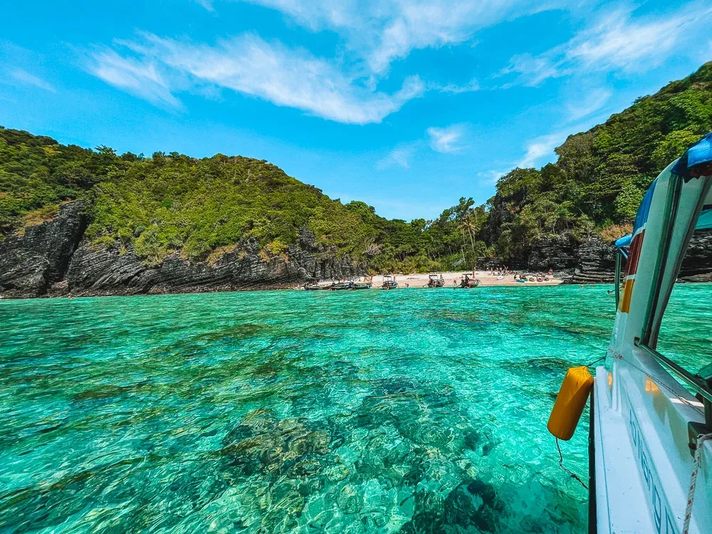 Clear turquoise waters and a boat near the shore at Maya bay near Phi Phi Islands, Thailand.