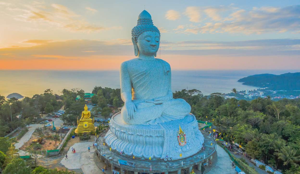 The Big Buddha statue in Phuket, Thailand, overlooking the coastline at sunset.