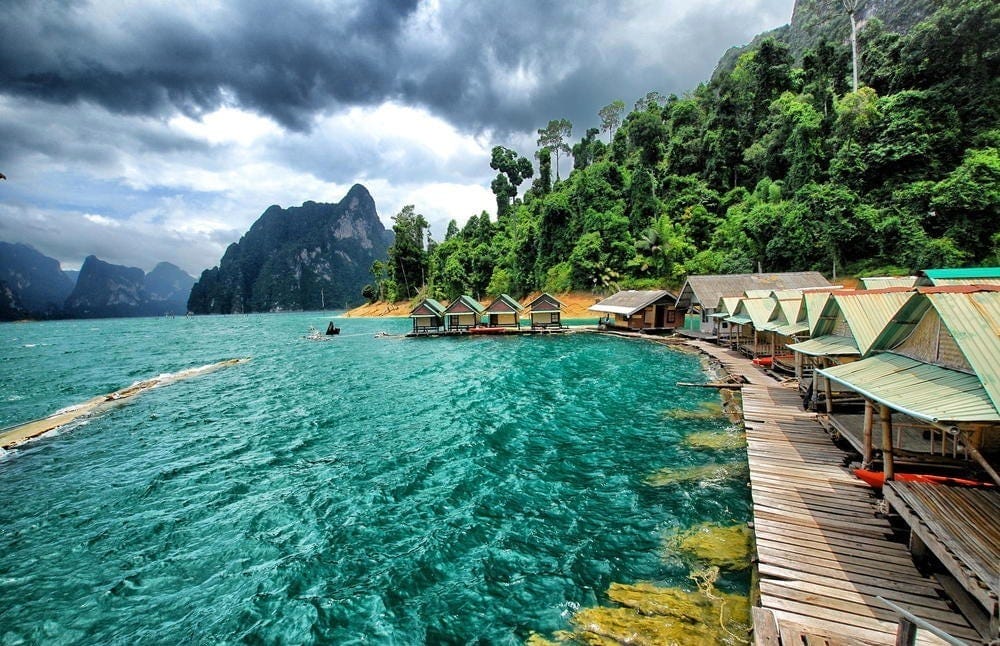 Floating cabins line the emerald waters of Cheow Lan Lake beneath lush limestone cliffs.