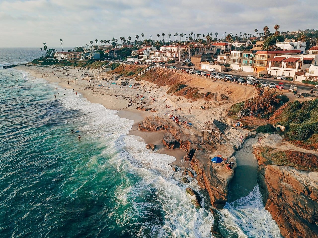 View of waves crashing onto the beach where people are relaxing at Windansea beach in San Diego, California.