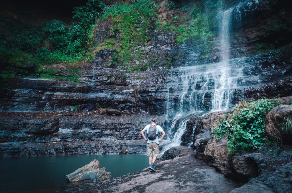 A hiker looking at a pool of water formed from Cascadas de Juan Curí waterfall in Colombia.