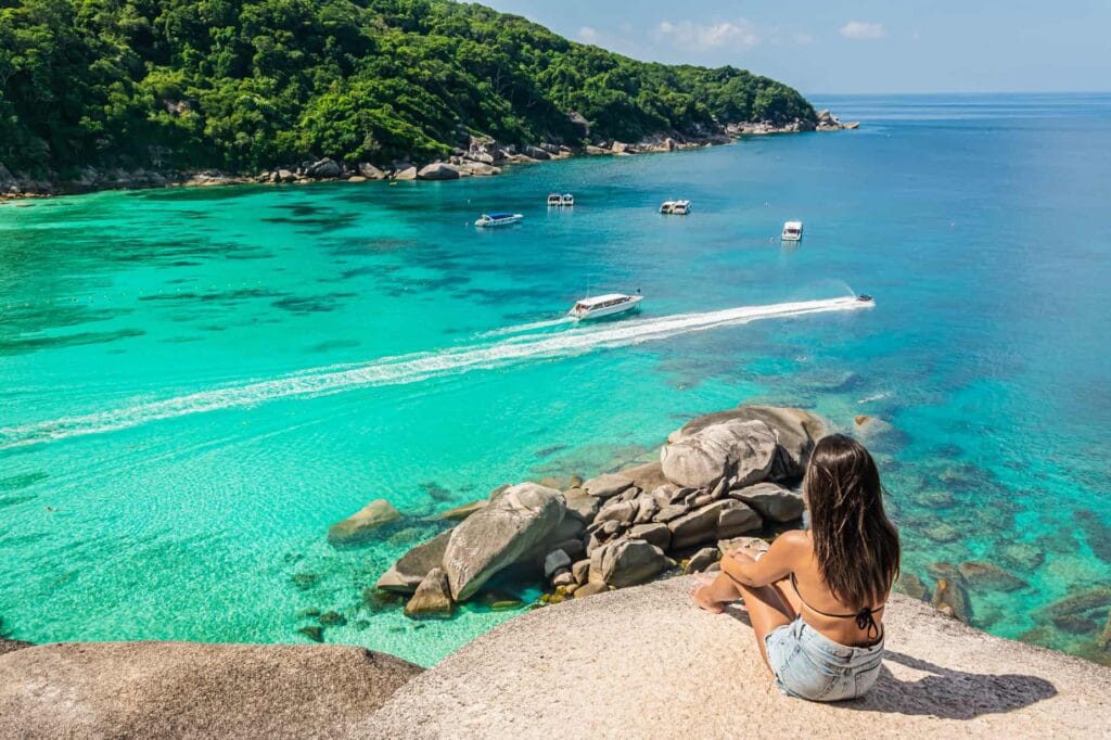 Girl sitting on top of a rock over looking clear blue waters at Mu Ko Similan National Park