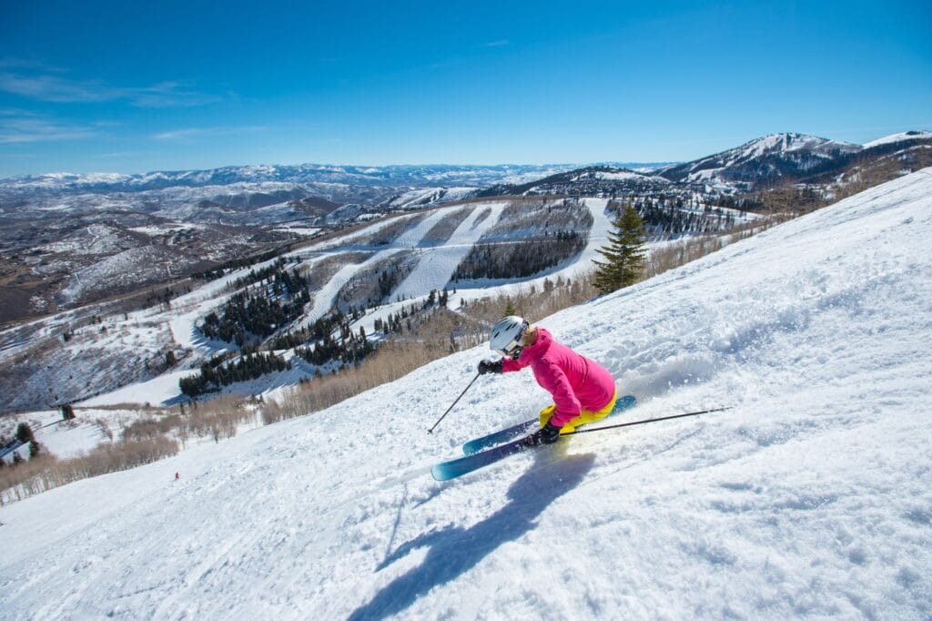 Woman wearing a pink ski jacket skiing down a slope at Park City Ski Resort