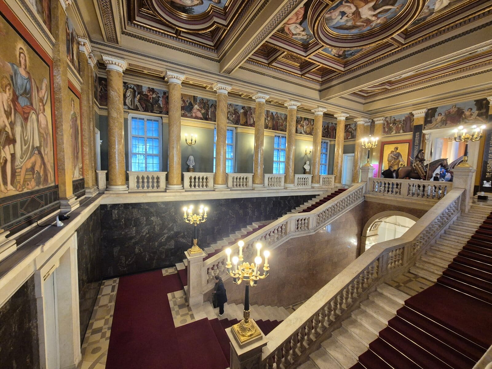 Hungarian National Museum interior stairs surrounded by artwork on the walls and ceiling.