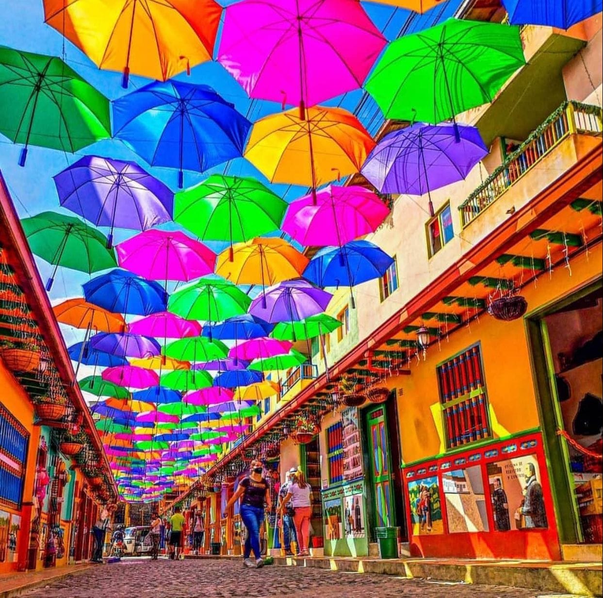 Colorful buildings in Plazoleta de los Zocalos with umbrellas hanging above the street.