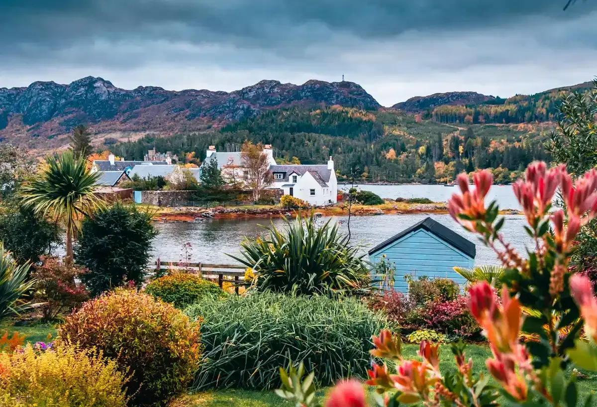 plockton village uk on a sea front surrounded by colorful flowers.