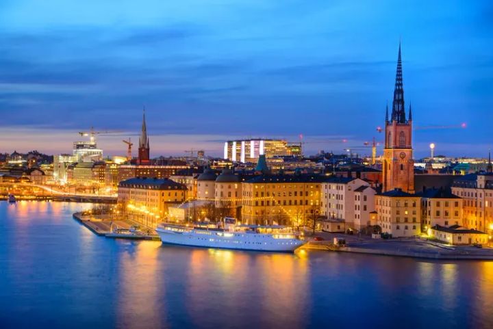 Stockholm, Sweden at night light up with lights and a white ship anchored in the harbor.