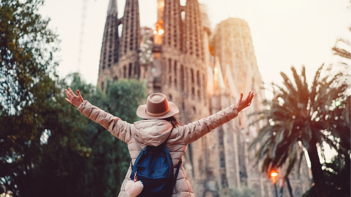 Woman holding up her hands in front Basílica de la Sagrada Família in Barcelona, Spain. 