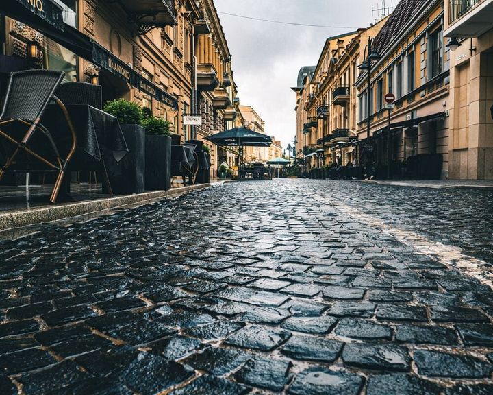 Street level view of an old cobblestone street that is lined with cafes for people to eat at in Lithuania.