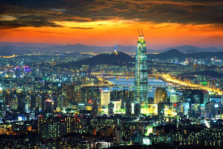 View of Seoul, South Korea at night with the city lit up, with the sun nearly set behind the Sky Observation desk.