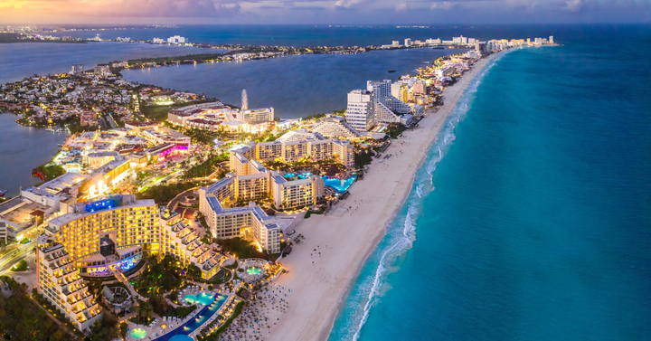 Ariel View of Cancun's Hotel Zone At Dusk showing the beach and clear blue waters.